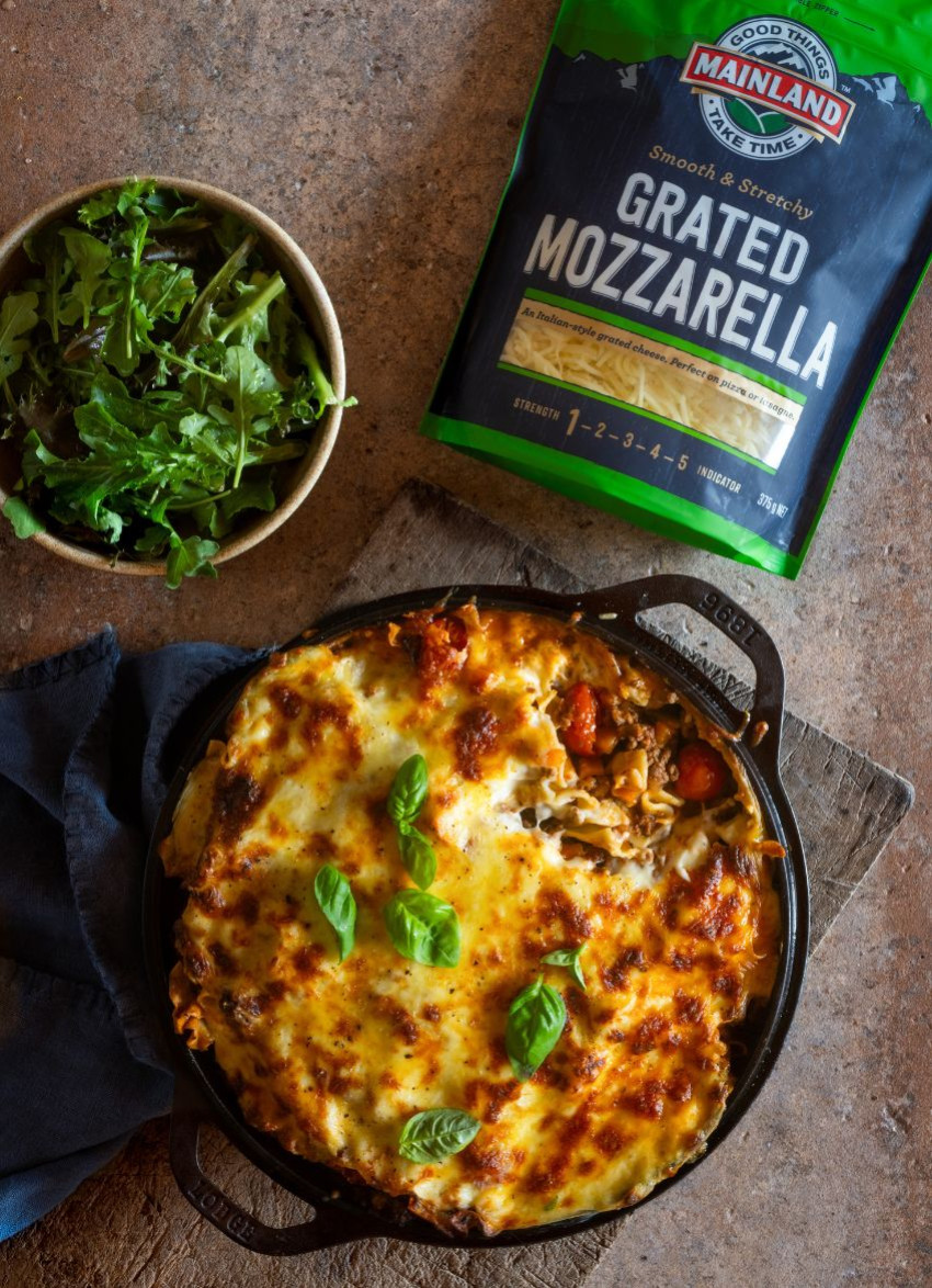 Layered beef and cherry tomato lasagne in a baking dish